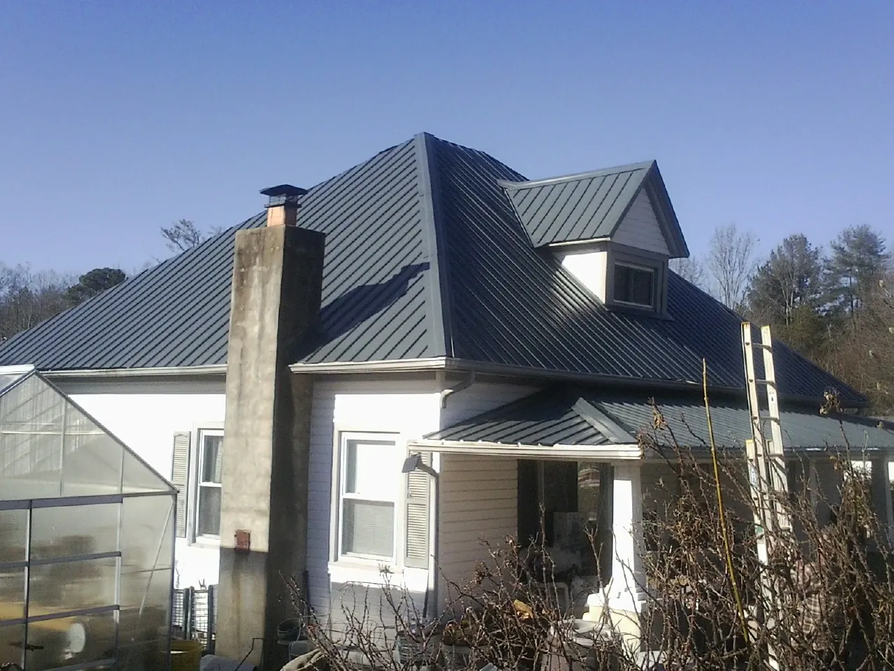 Dark blue standing seam metal roof on a white farmhouse with dormer — Slate & Tile Roof Repair by Roofing Brothers in Kerhonkson