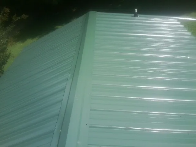 New green metal panels meeting at the ridge of a roof — Flat Roof Repair work by our crew in Kerhonkson
