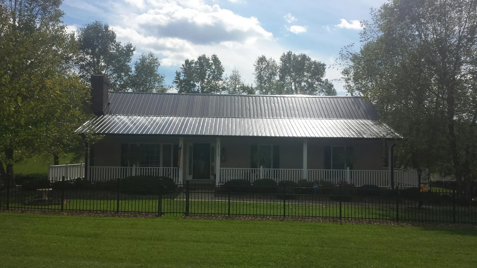 Gray metal roof on a brick ranch with a full width front porch — Gutter Guard Installation work by our crew in Kerhonkson