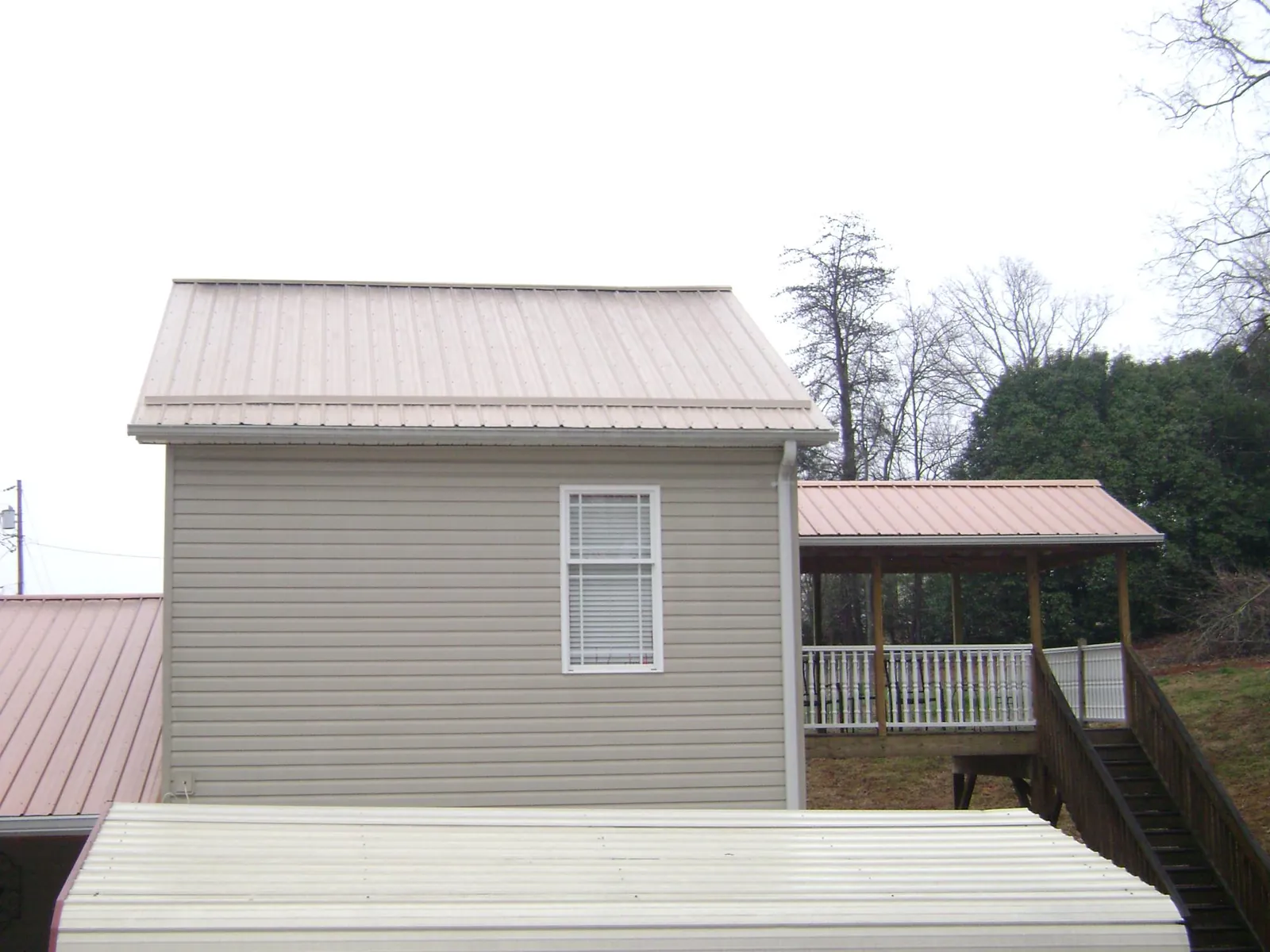 Tan metal roofs on a two story addition and attached porch, from a Roof Replacement job in Kerhonkson