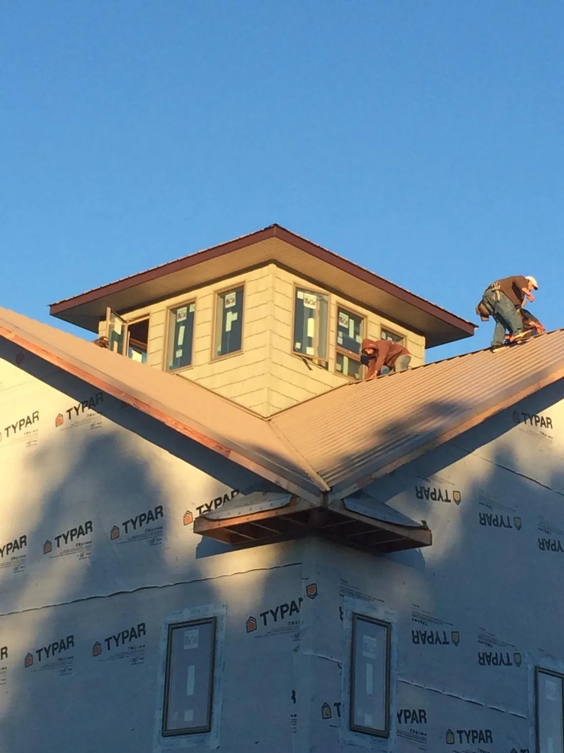 Roofers working around a rooftop cupola on a new metal roof at sunset — Roof Waterproofing in Kerhonkson by Roofing Brothers